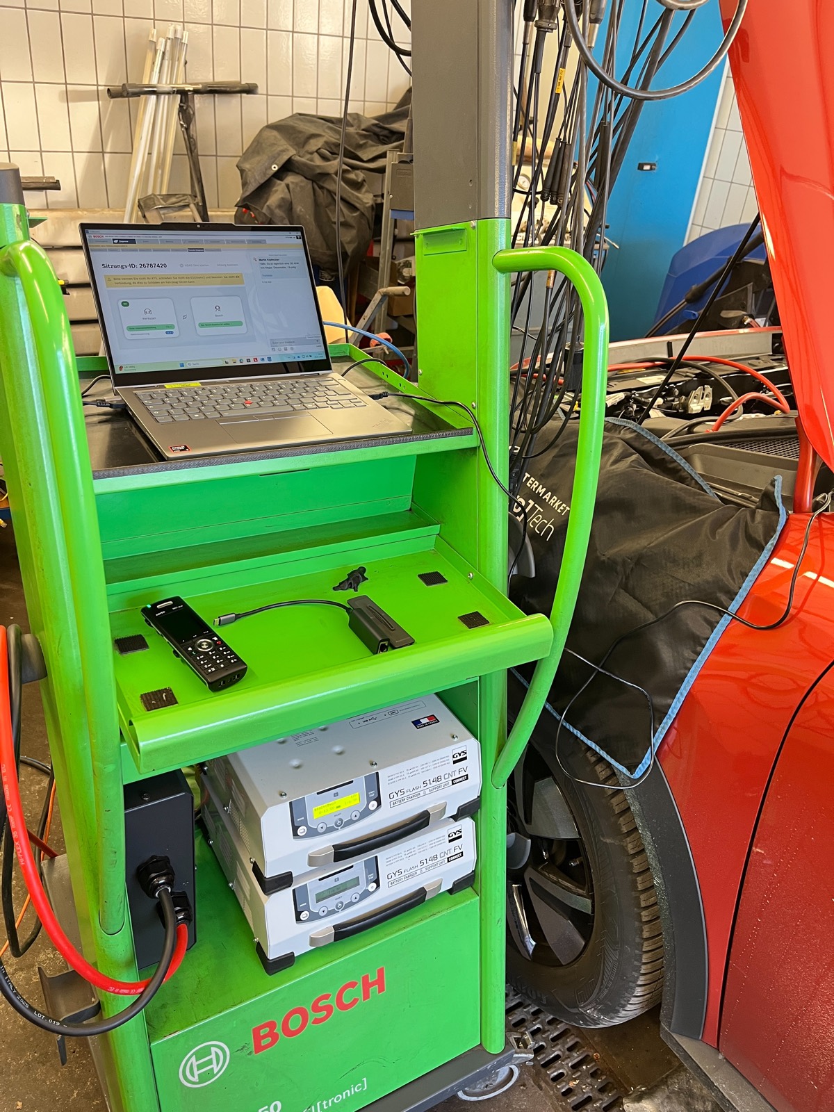 Mobiler Bosch-Diagnosewagen mit Laptop an einem roten Fahrzeug in unserer Werkstatt.